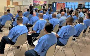 Corcoran prison ARC program participants sit in chairs at a graduation.
