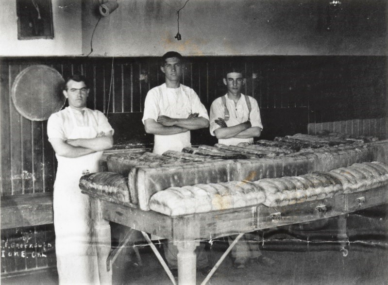 Incarcerated youth in a bakery kitchen with loaves of bread.