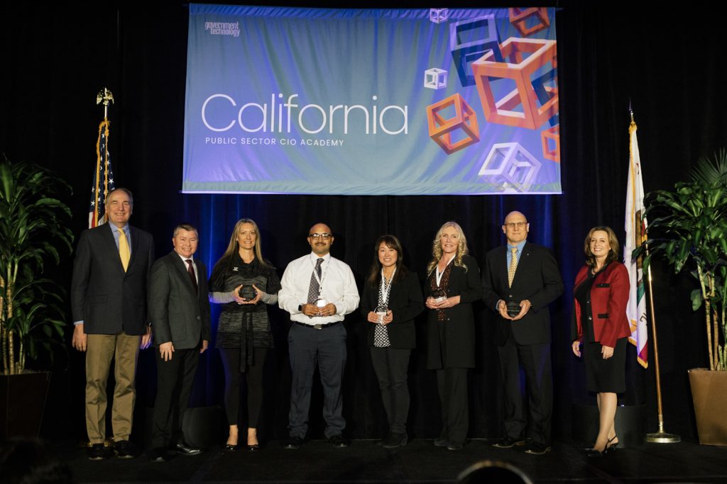 People stand on a stage under the California CIO Academy banner at the leadership awards.