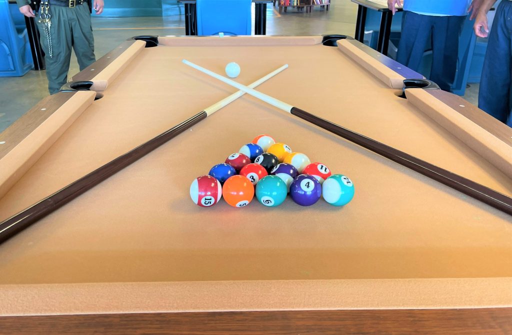 A pool table with pool balls and crossed pool cues.