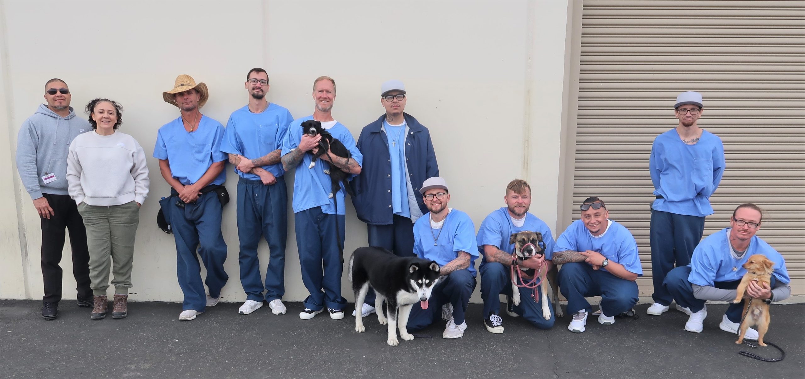 Dogs at Avenal State Prison (ASP) with their incarcerated trainers and two people from a nonprofit organization.