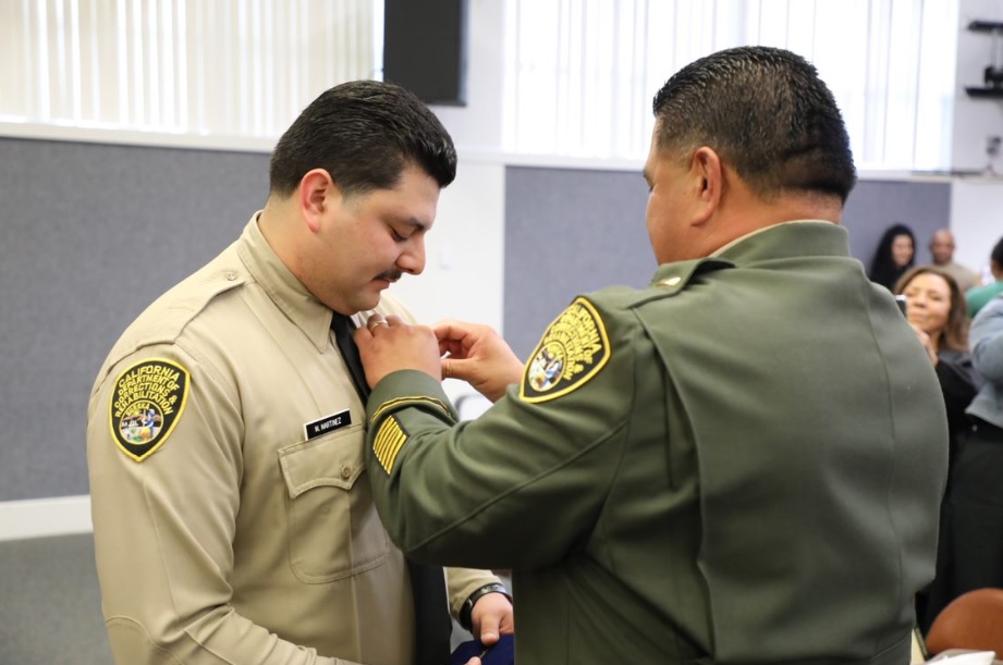Father bins correctional officer badge on his son.