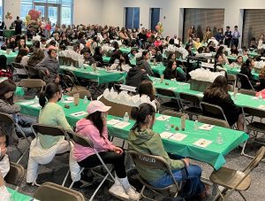 Girls sitting at tables in a large hall.