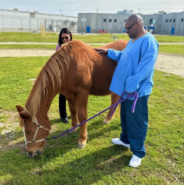 Prison warden, a horse and an incarcerated person on a prison yard.