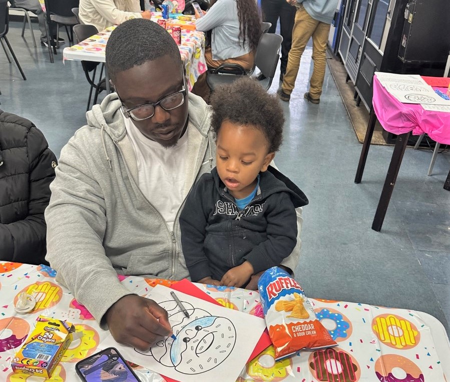 A reentry program participant and his child color a doughnut at Donuts with Dad.