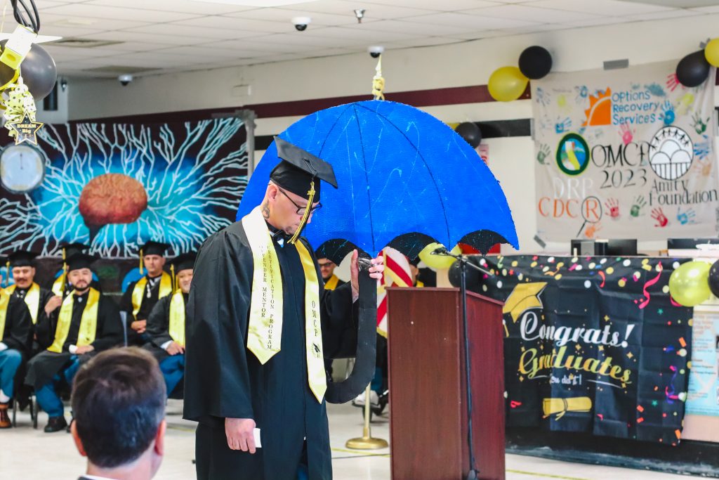 A graduate carries a crafted umbrella to signify the storms hitting the area which they adopted as their graduation theme.