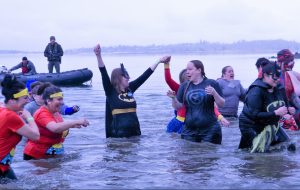 Polar Plunge for Special Olympics with people waist deep in a lake while wearing superhero costumes.