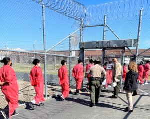 At-risk students wearing red coveralls enter the Valley State Prison (VSP) gates.