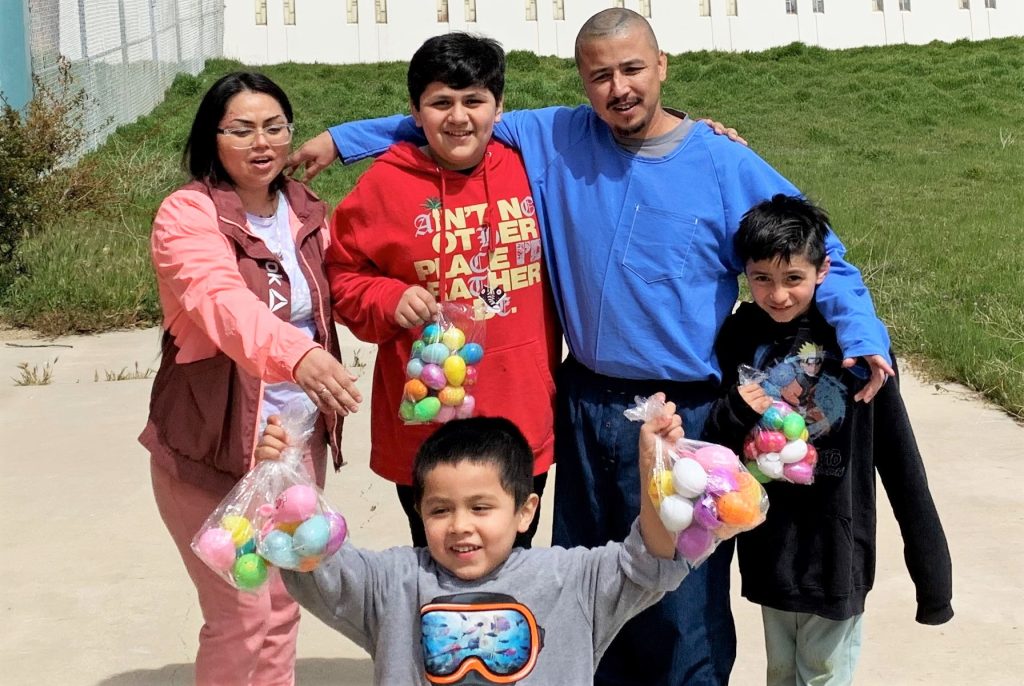A family in a prison visiting area with Easter eggs.