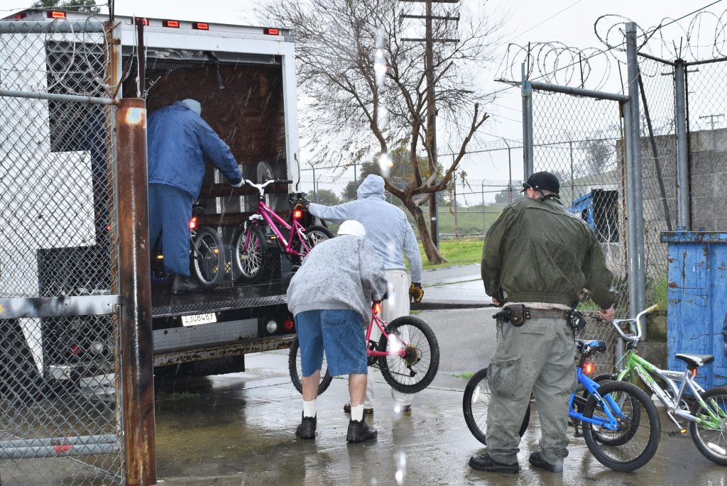 People line up to load bicycles into back of truck.