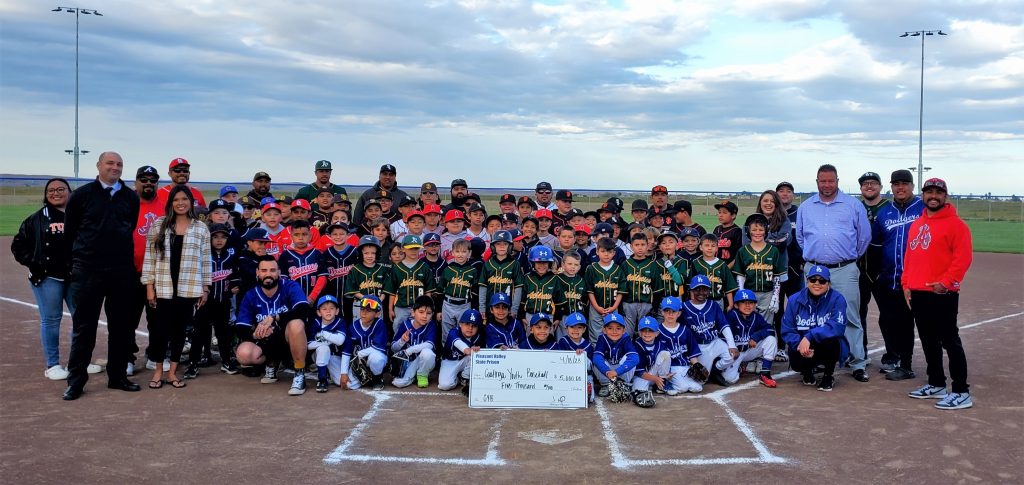 Prison staff present a check to Little League youth baseball teams, one of many charities incarcerated and staff raise funds to donate.