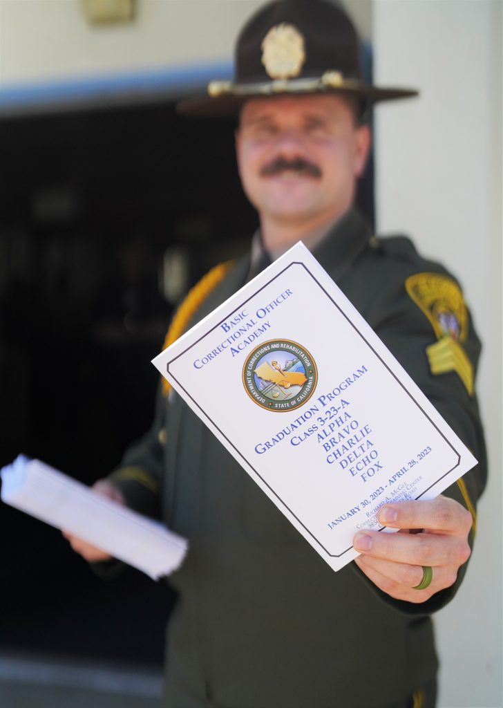 Graduation pamphlet being handed out at entrance to correctional officer academy.