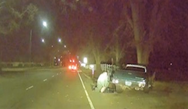 Dash cam photo of man performing CPR on a man involved in a car crash.