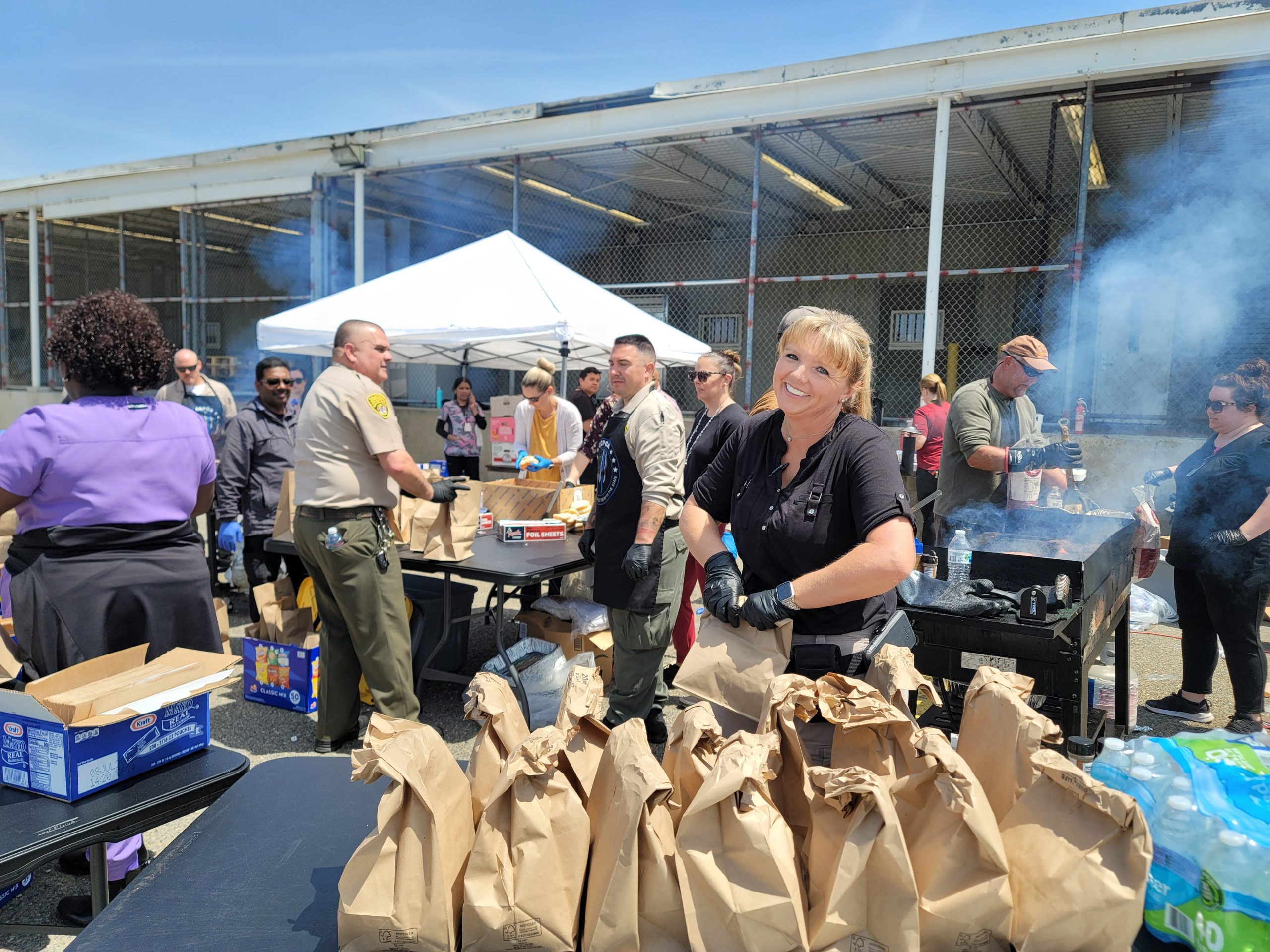 Prison staff working a grill and bagging food for employees.