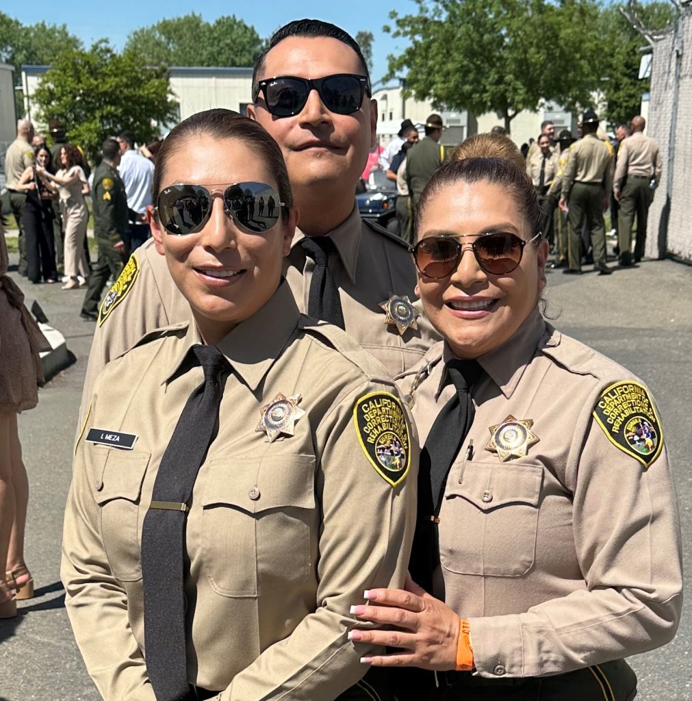 Three siblings who are CDCR correctional officers hug the academy graduate.