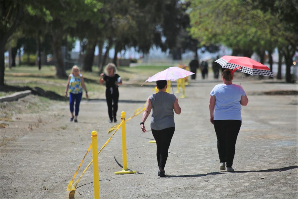 Two prison staff holding umbrellas walk on a track at California Men's Colony (CMC). 