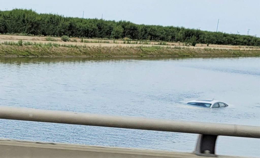 Car mostly submerged in canal.