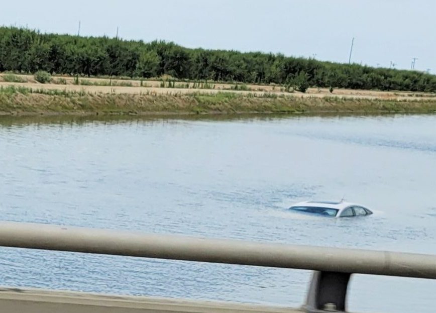 Car mostly submerged in canal.