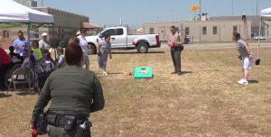 A correctional staff member tosses a bean bag at a corn hole board.