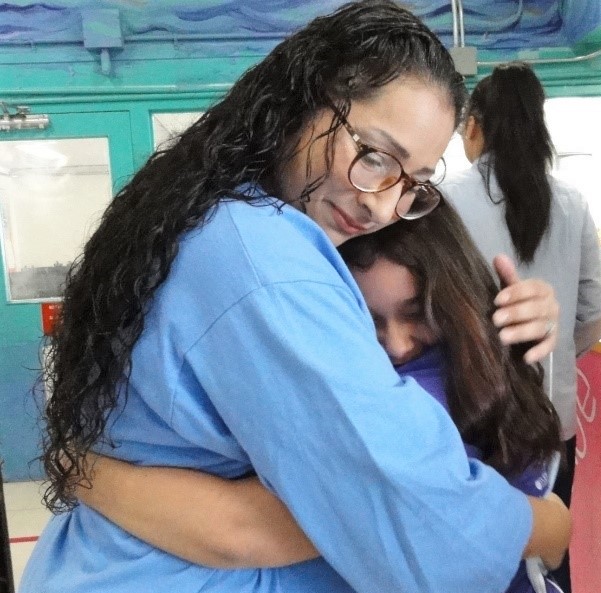 An incarcerated parent hugs her child at a prison.