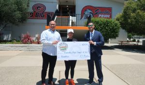 CTF and the incarcerated population helping a school with a donation. Three people hold an oversized check.