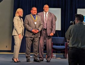 Luis Cardenas receiving the Gold Star, standing between a cabinet secretary and the director of the parole division.