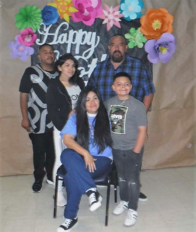 Staff created Mother's Day backdrop as an incarcerated mother, three children and a father pose for a  photo inside a prison.