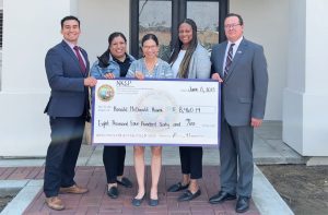 North Kern State Prison (NKSP) staff and two people from Ronald McDonald House with an oversize donation check.