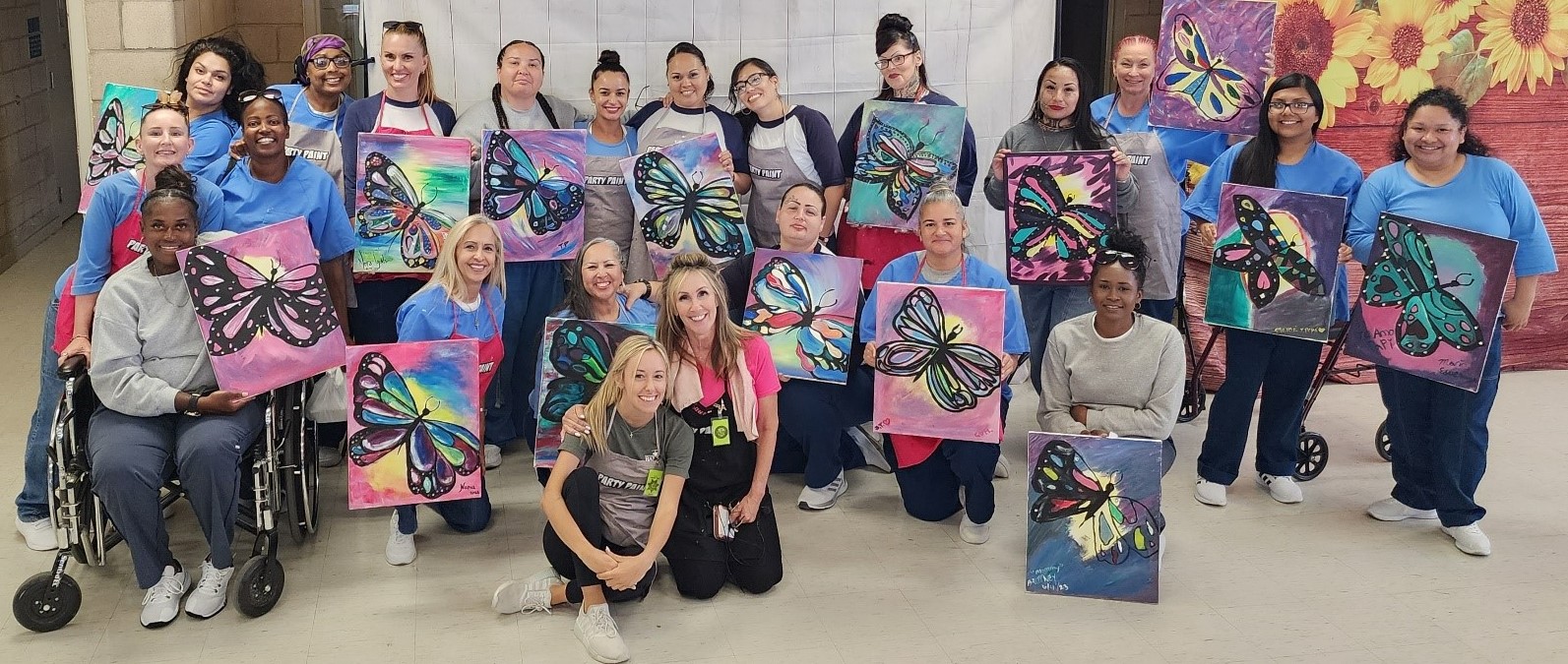 group of incarcerated holding paintings from CCWF paint night