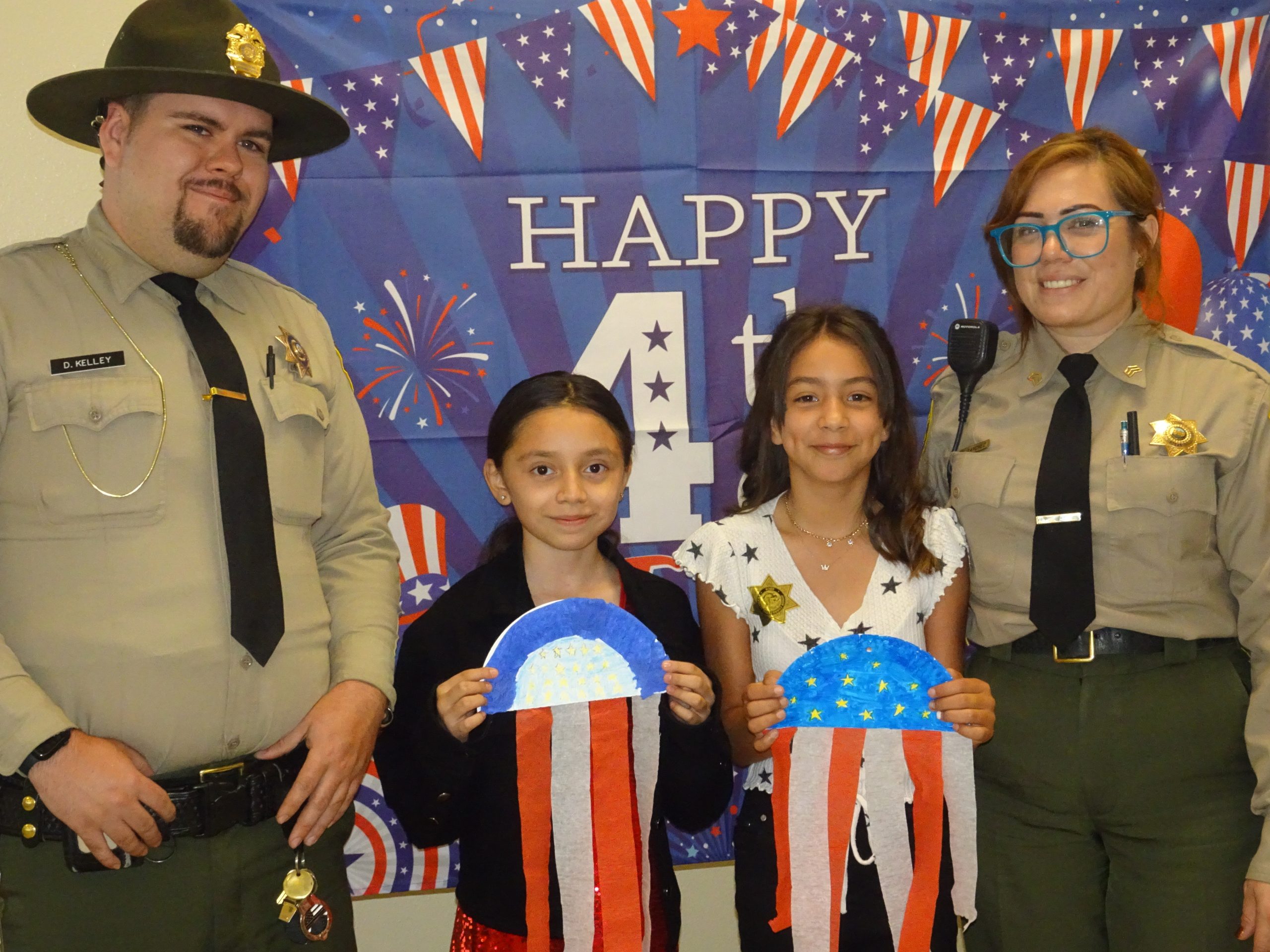 Two children with Fourth of July crafts and ASP officers.