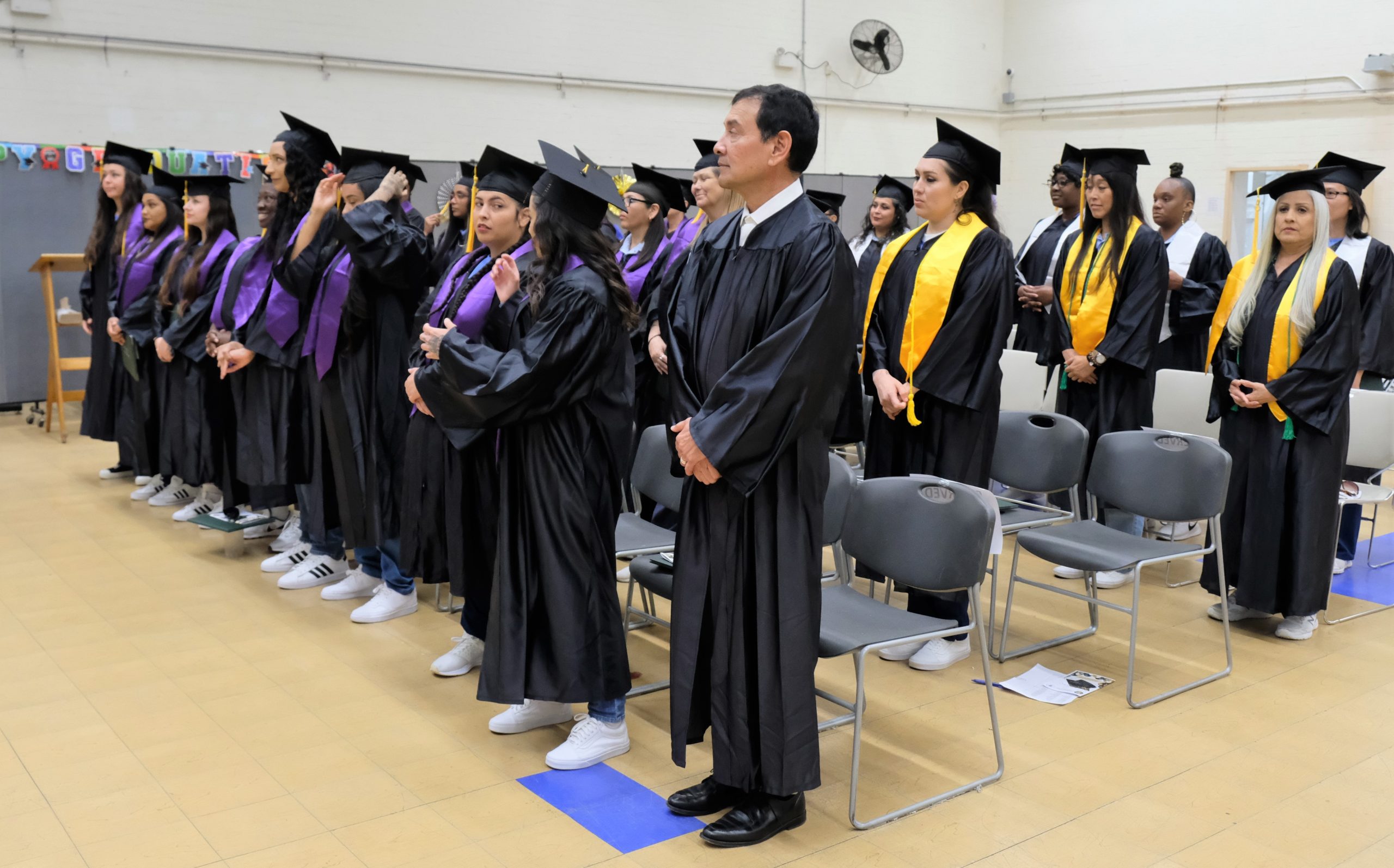 Graduates wear caps and gowns in a ceremony in CIW.