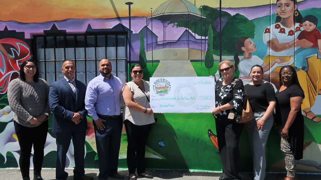 Prison officials present a donation check to a local arts center.