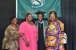 Four people at MCSP stand in front of a Sacramento State University banner.