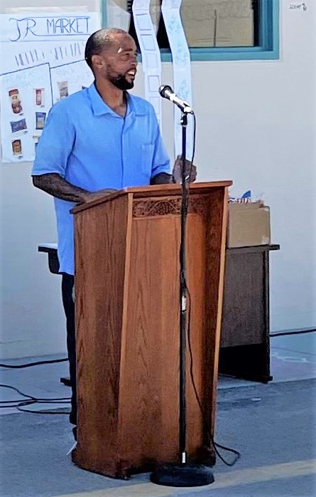 An incarcerated man speaks at a lectern.