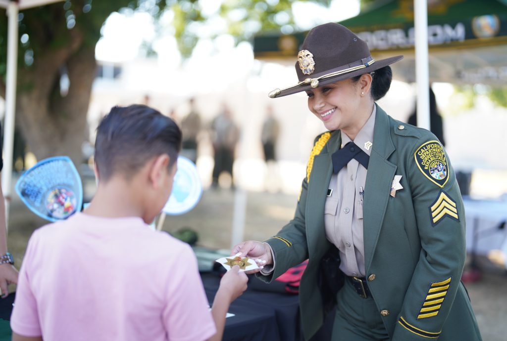 A correctional sergeant speaks to a young person at a recruitment booth.