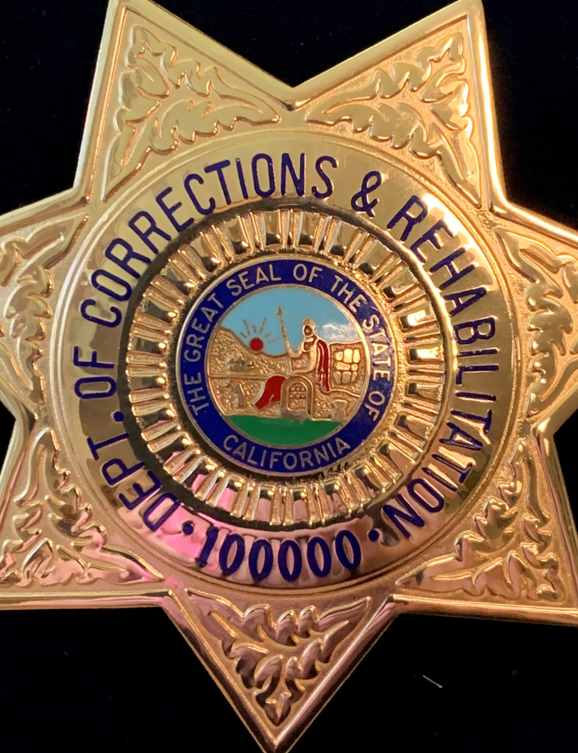 CDCR badge with the number 100,000 at the bottom.