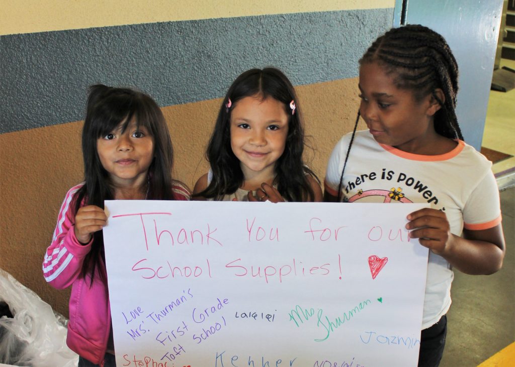 Three young students hold a thank you sign.