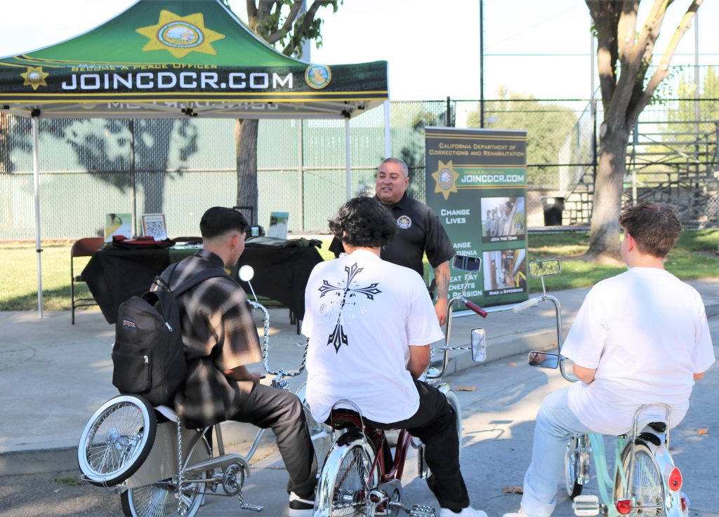 CDCR sergeant speaks to three youth on bicycles at a park in Galt.