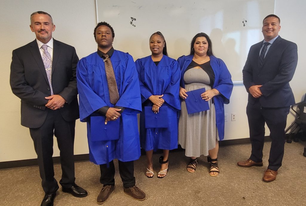 Three pre-apprenticeship program graduates with two parole staff members.