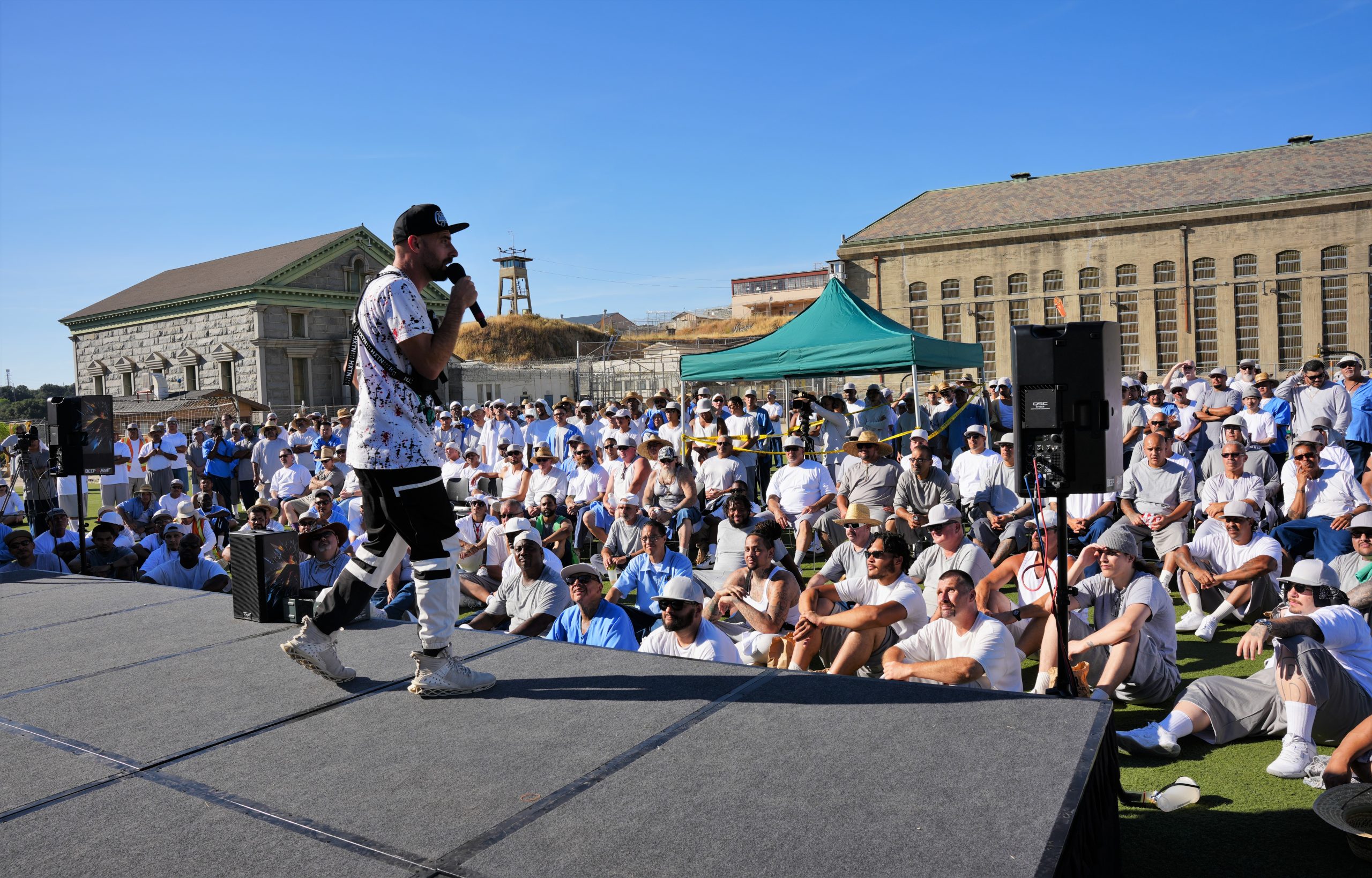 A man performs on a stage in front of an audience at Folsom State Prison (FSP) as part of Summer Palooza.
