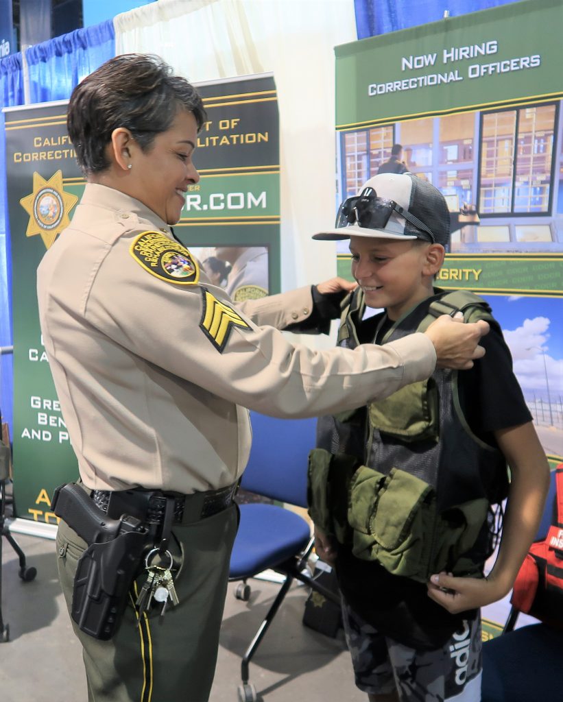 CDCR sergeant and a kid at a recruitment booth.