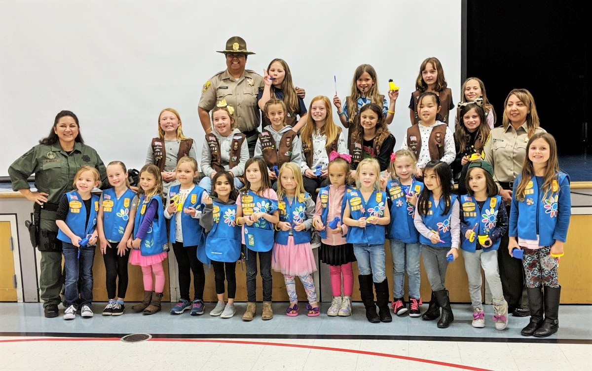 Girl Scouts and three correctional staff wearing uniforms.