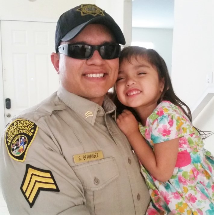 A correctional sergeant holds his young daughter.