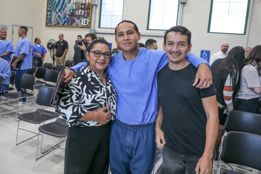 An incarcerated man with two family members at a graduation.