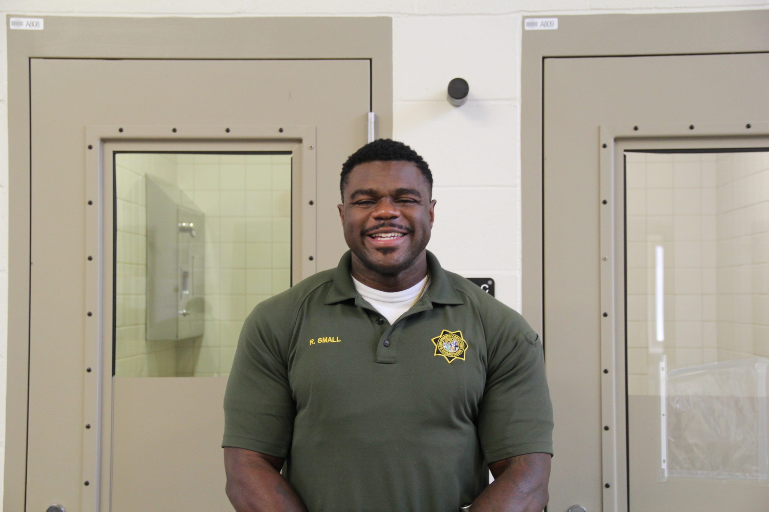 Officer Small standing in front of two prison cell doors.