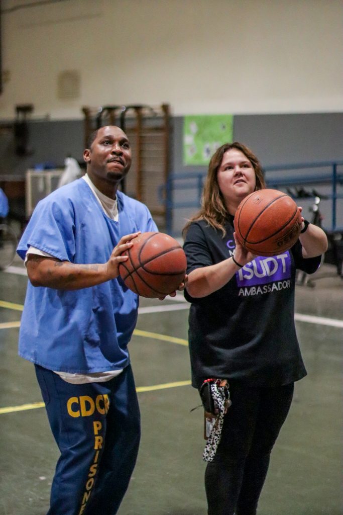 An incarcerated person and an ISUDT ambassador shoot hoops at California Medical Facility.