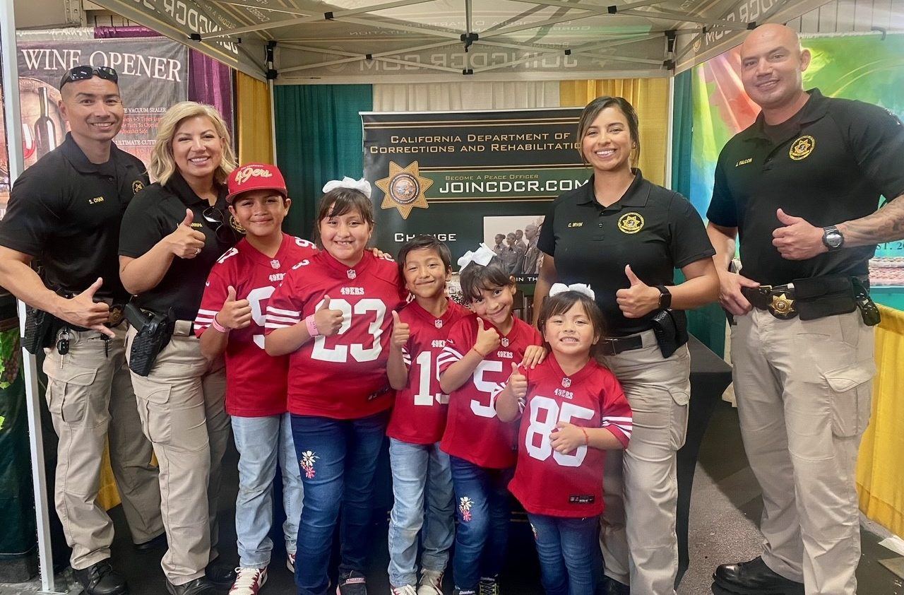 PVSP recruiters at Fresno Fair with kids wearing sports jerseys.