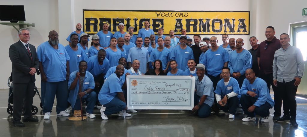 Incarcerated people hold an oversized check made out to Refuge Armona.