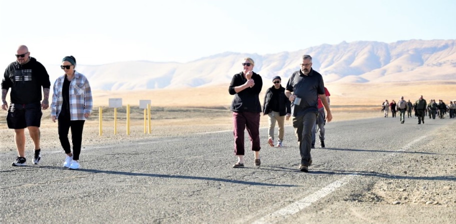 Prison staff walking on a paved road with mountains in the background.
