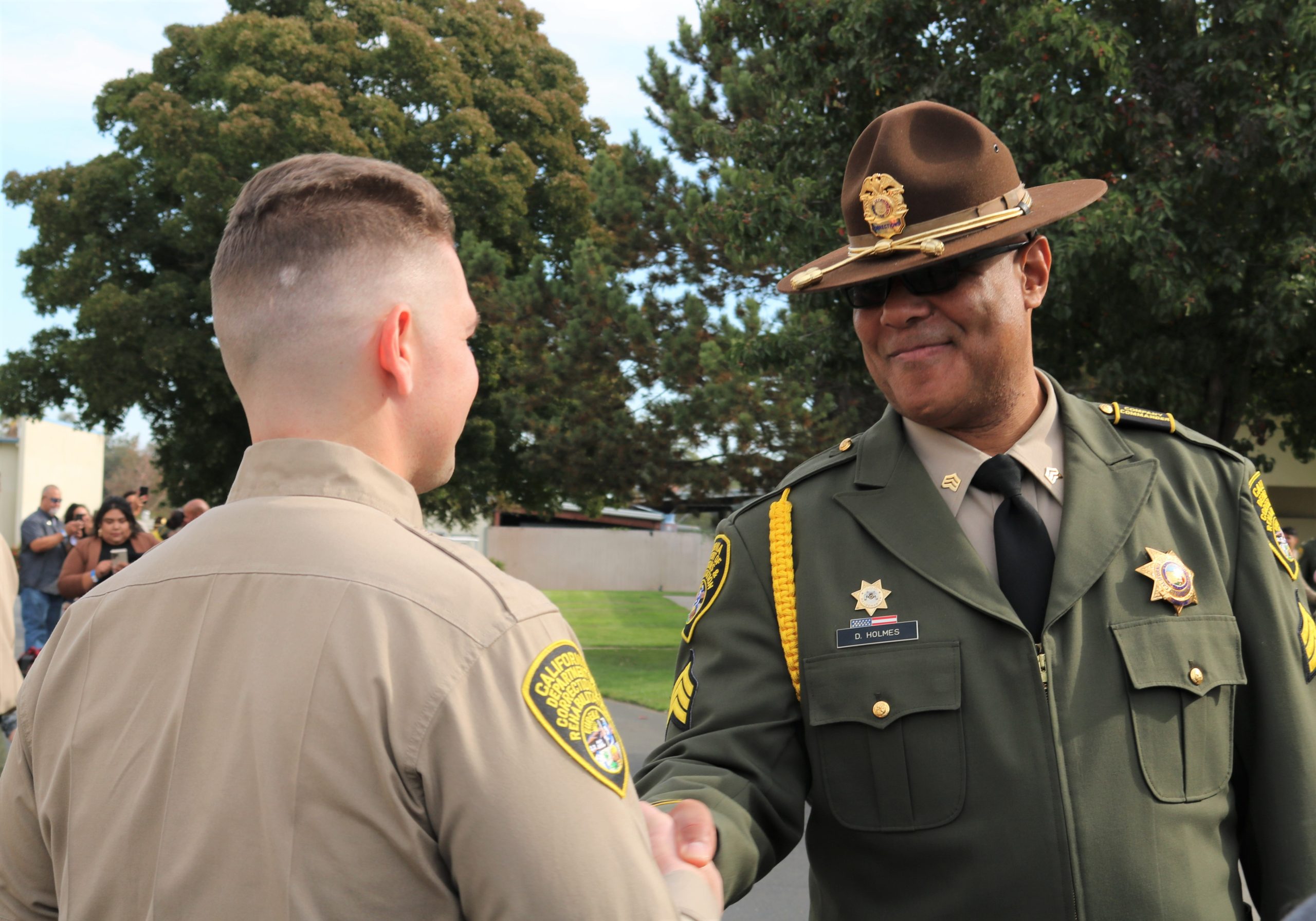 A CDCR sergeant congratulates cadet graduates from the Basic Correctional Officer Academy.